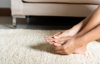 woman with foot ache holding her feet